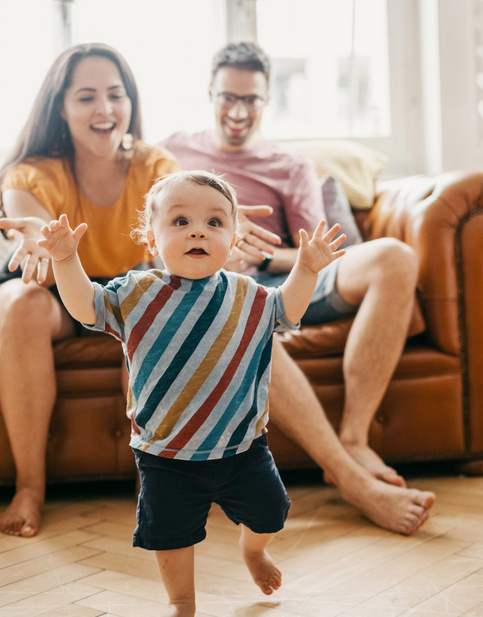 happy mom and dad watching their baby walk