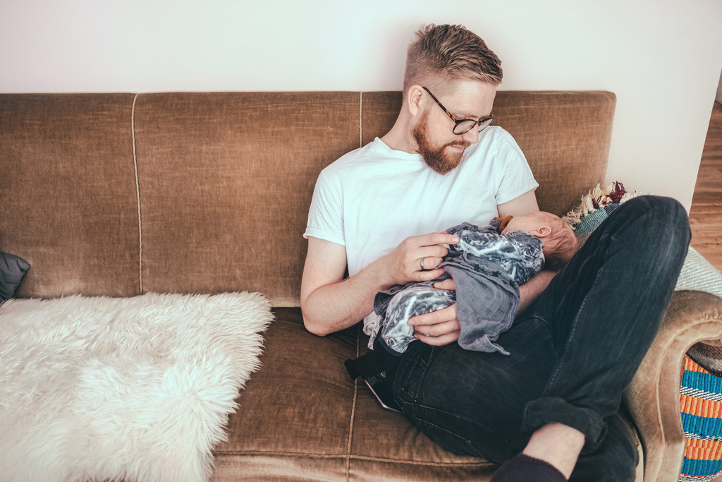 dad on the couch with sleeping baby on lap